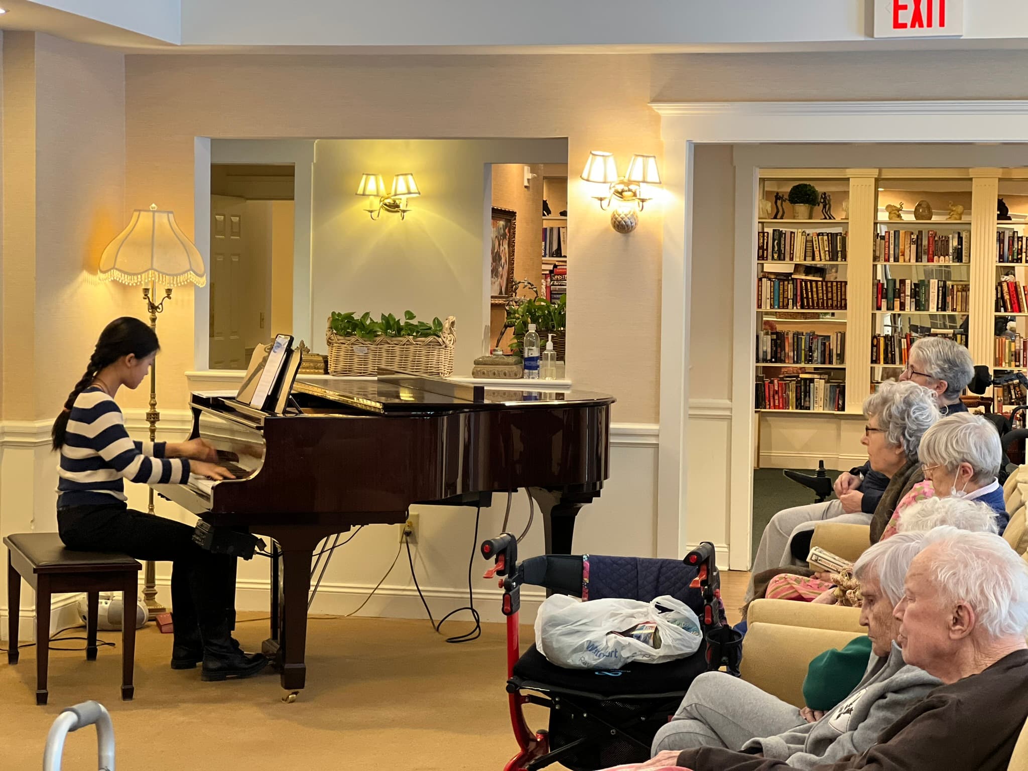 A young pianist performing for residents in a senior community