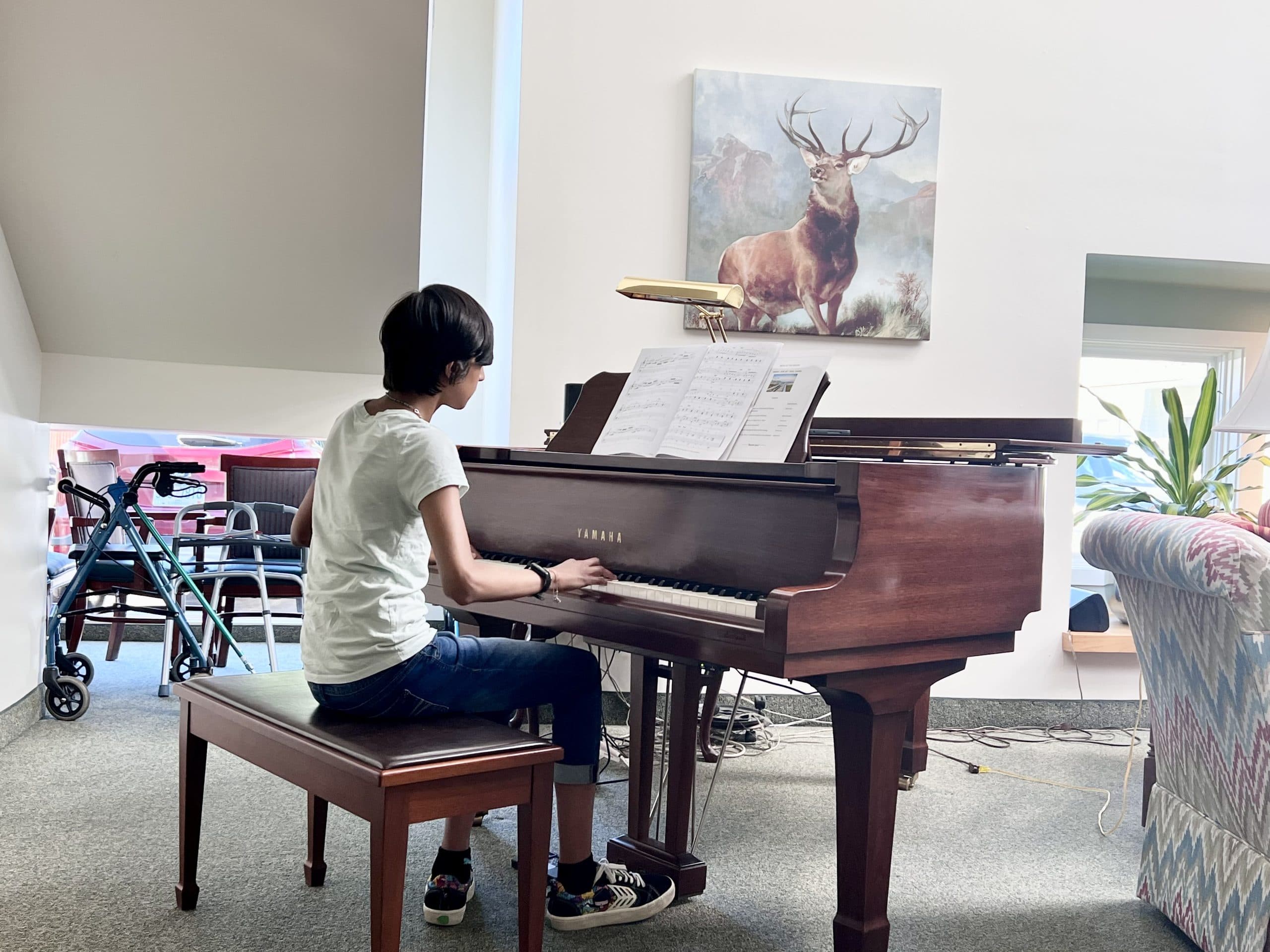 A student performs piano in a senior community
