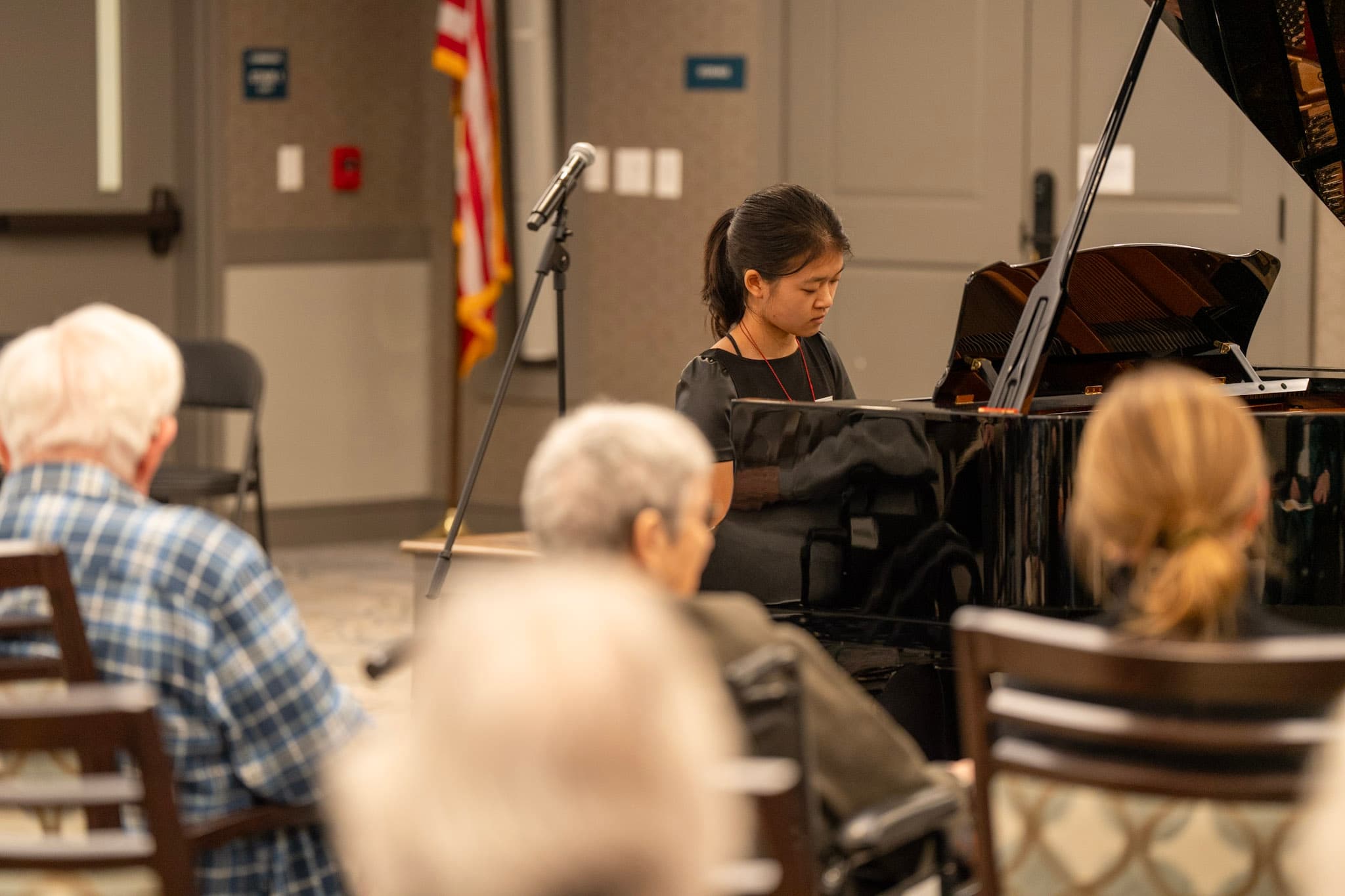 Grace performs piano for residents gathered in a senior community