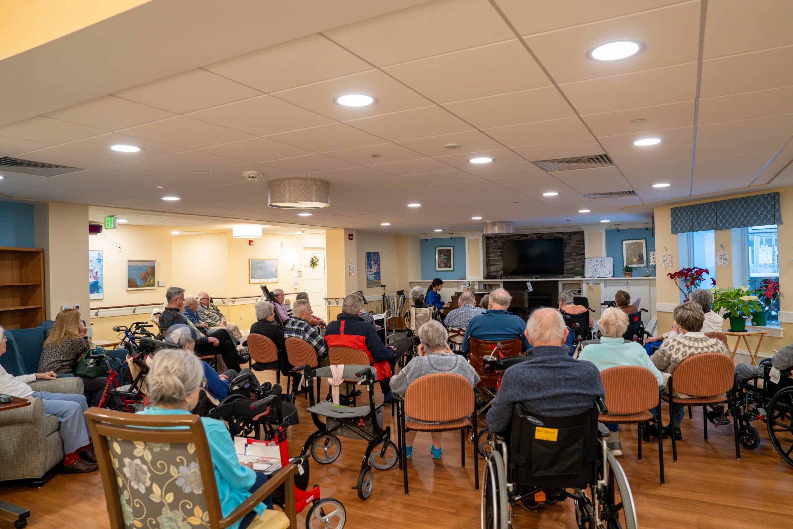A young pianist performs for a full room of older adults at Kendal at Hanover